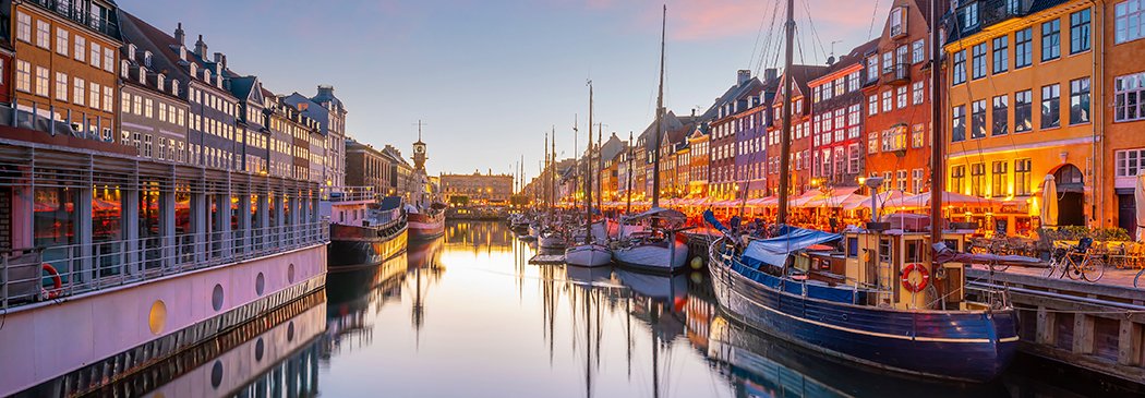 El puerto de Nyhavn en Copenhague al atardecer con barcos y edificios iluminados | MSC Cruceros
