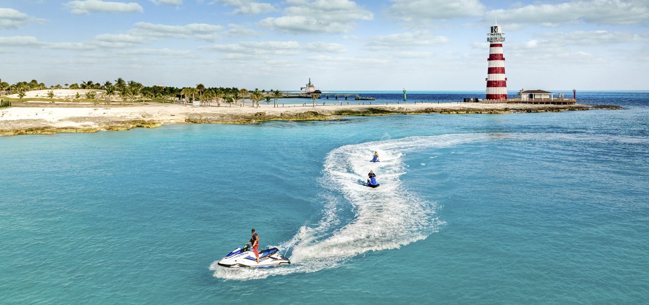 Jet skis near a lighthouse on a tropical island with clear blue waters | MSC Cruises Jet skis near a lighthouse on a tropical island with clear blue waters | MSC Cruises