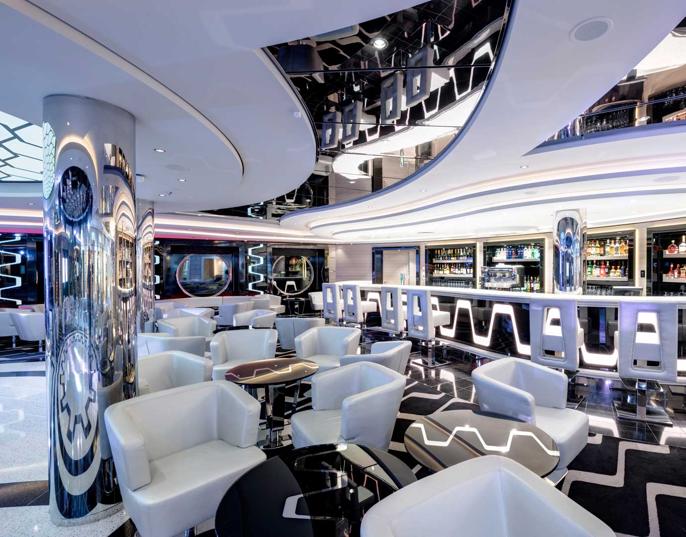Modern cruise ship bar with sleek white seating and illuminated counters | MSC Cruises Modern cruise ship bar with sleek white seating and illuminated counters | MSC Cruises