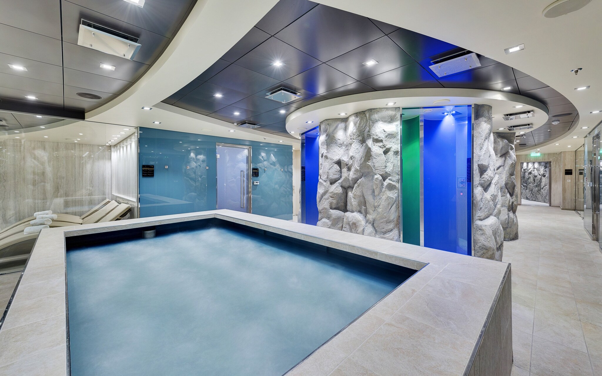Luxurious spa area with a thermal pool, stone walls, and relaxation loungers onboard | MSC Cruises