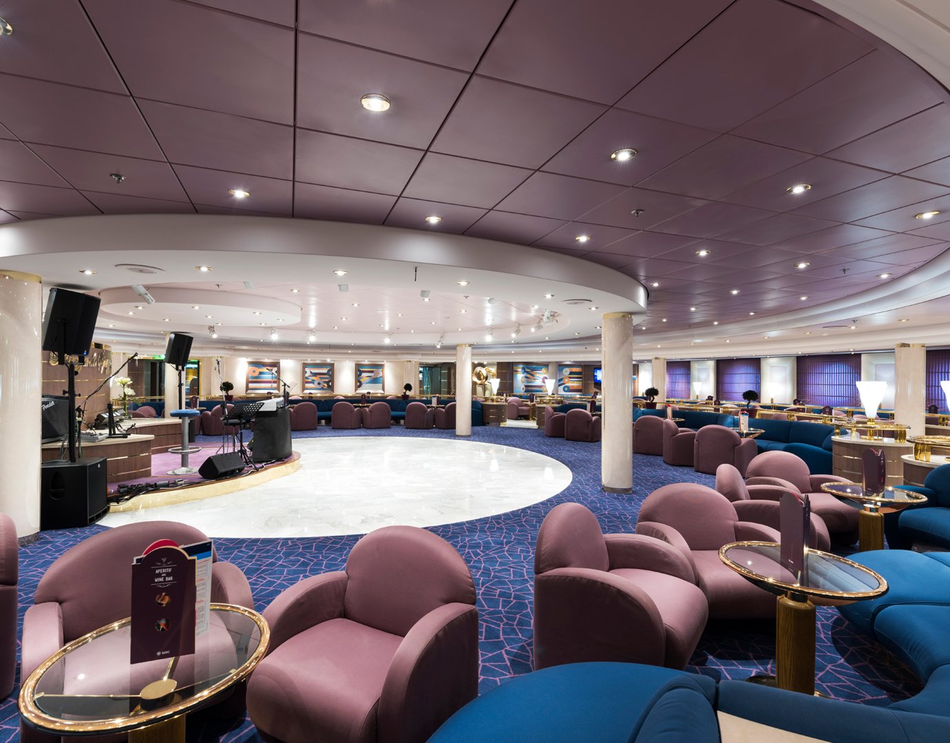 Elegant lounge with purple seating and stage area onboard a cruise ship | MSC Cruises Elegant lounge with purple seating and stage area onboard a cruise ship | MSC Cruises